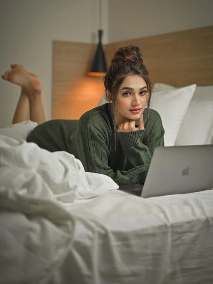 Reeshma Nanaiah working on her laptop lying on her bed